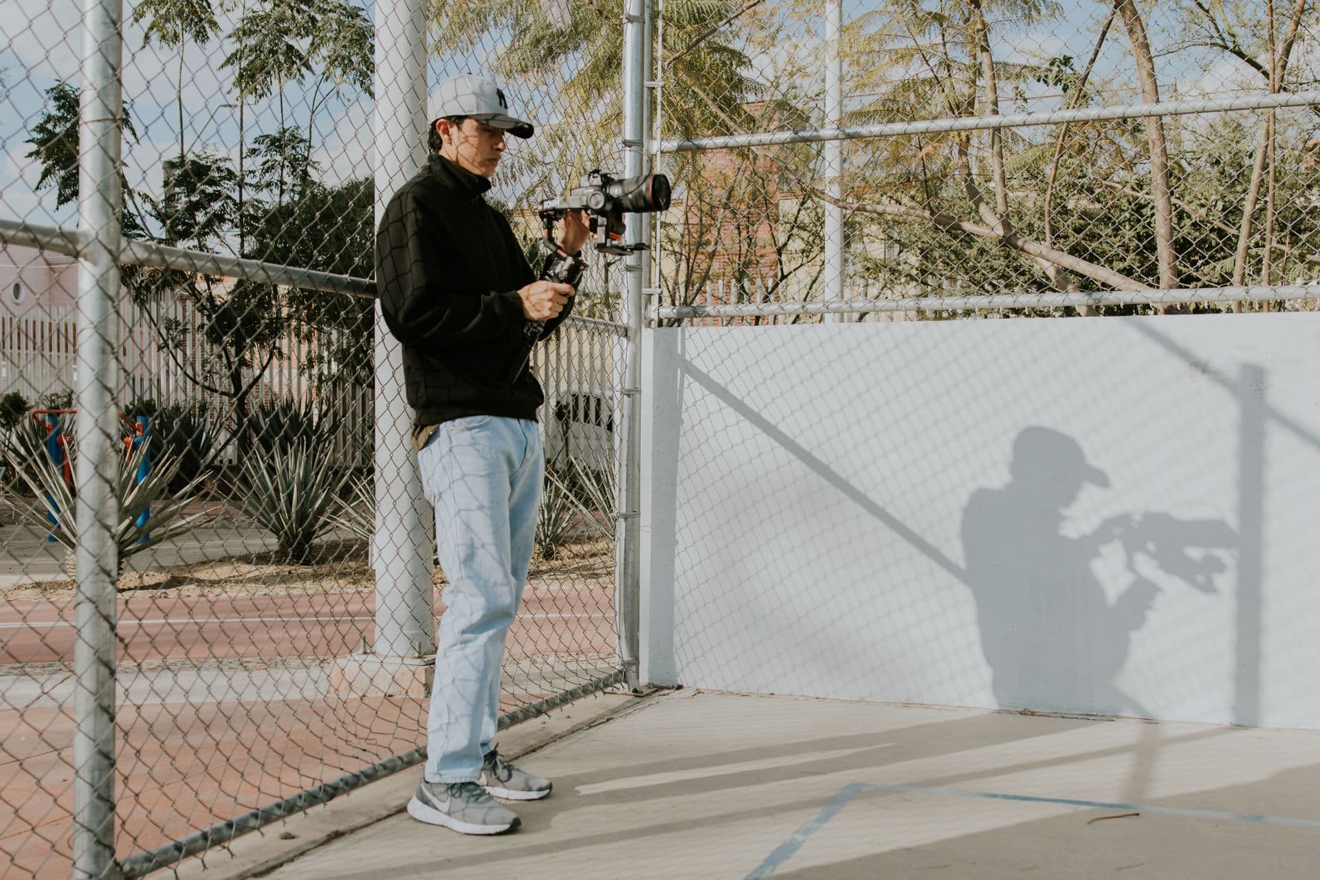 Young filmmaker with camera on an outdoor court